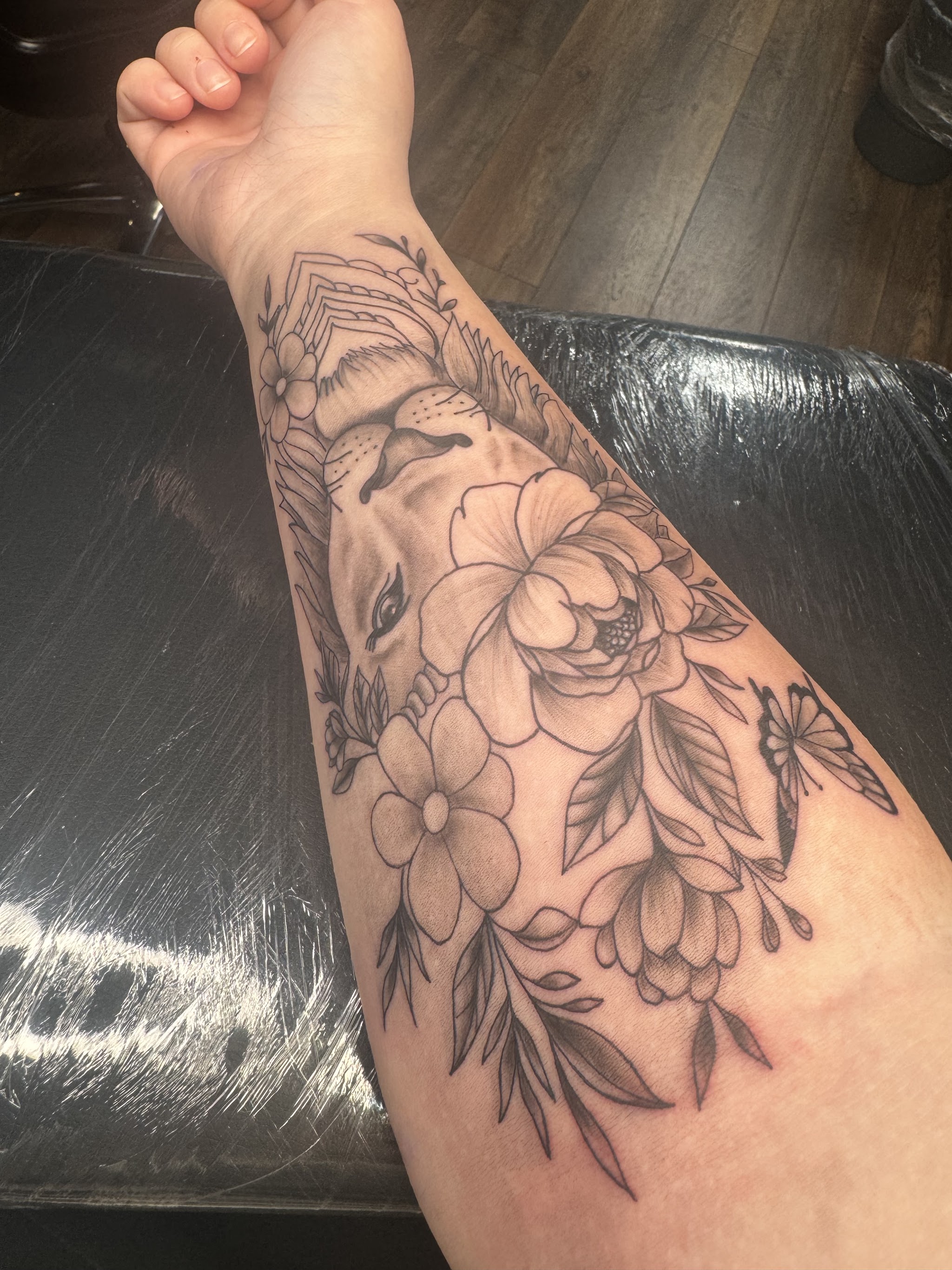 Realistischer Löwenkopf mit Blüten am Unterarm