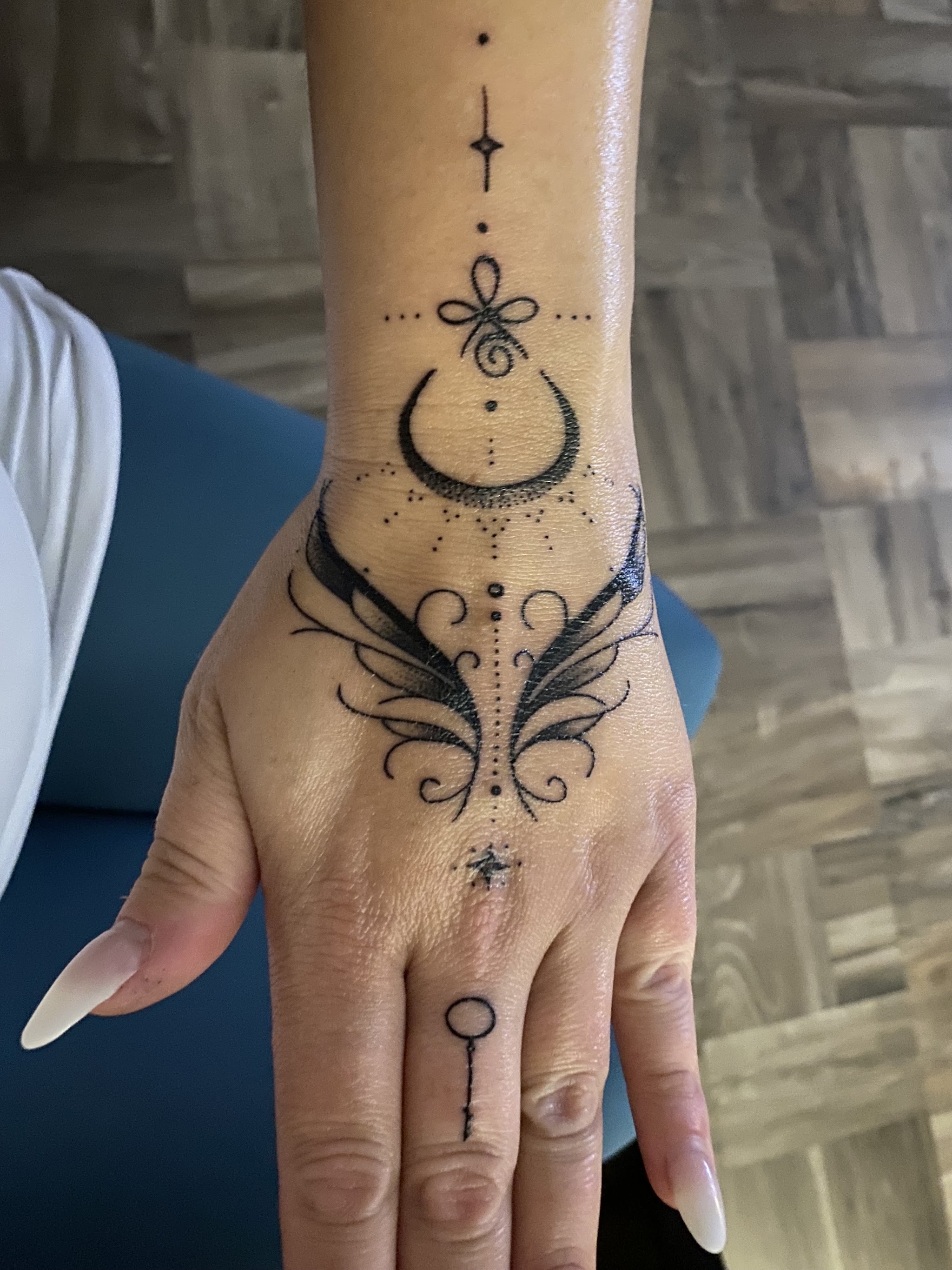 Fineline-Tattoo mit Mond und Sternen auf dem Handrücken